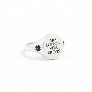 Silver signet ring with oval face engraving and a blue gemstone set on the side