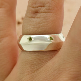 Faceted metal band ring with two green gem eye insets on top