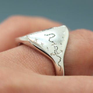 Silver signet ring with etched star-and-arc pattern on the band