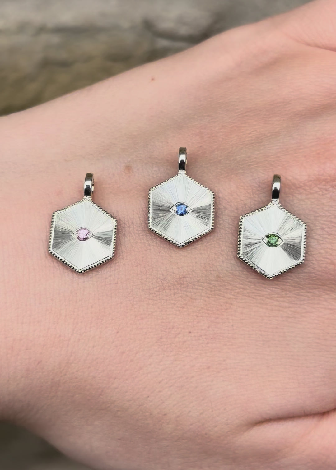 Three silver hexagon shape pendant necklaces with pink sapphire, sri lankan blue sapphire and natural green diamond  set eyes with Guilloché hand engraved sun burst pattern and milgrain border - Emily Proudfoot 