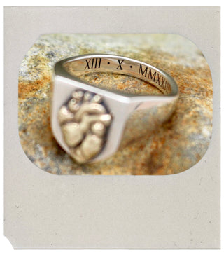 Silver ring with engraved design on a textured stone background