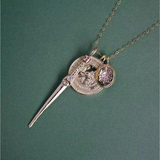 Charm necklace with circular medallion, dagger pendant, and flower charm on chain